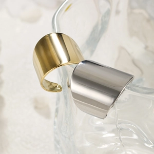 Detailed view of polished gold and silver open rings on a glass edge for a minimalist look