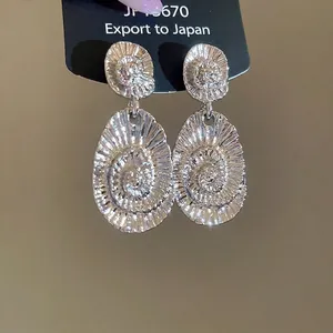 Silver metallic oval earrings with radial spiral texture and minimalist stud design