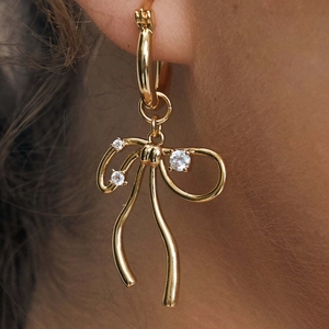 Gold bow earrings with clear zircons on a model, elegant hoop style for women