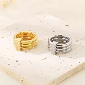 Close-up of interlocking 18k gold and silver plated rings with rectangular zircon detail
