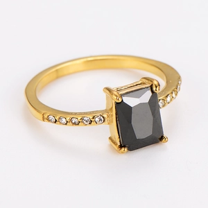Macro view of gold ring featuring a rectangular black gemstone and side zircon accents