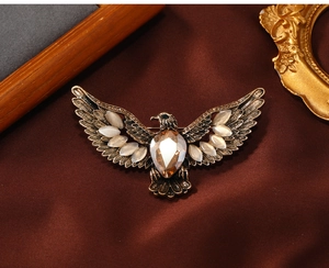 Detail of vintage eagle brooch with cat eye stones on dark silk fabric background