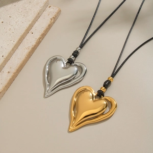 Détail de pendentifs en forme de cœur or et argent avec colliers cordon noir sur pierre