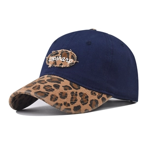 Détail de la casquette bleu marine avec visière léopard et écusson brodé sur le devant