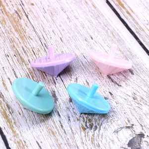 Top view of four colorful plastic spinning top toys in purple pink green and blue