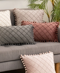 Close-up of diamond quilted velvet pillows with pom-pom fringe in multiple colors