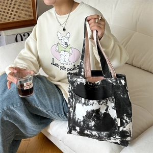 Dettaglio della borsa tote in tela con motivo tie-dye bianco e nero e tasca frontale pratica