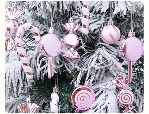 Pink and white Christmas tree ornaments including candy canes and lollipops on snowy branches