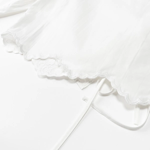 Detail of white cotton blouse showing wavy embroidered lace hem and adjustable tie cord