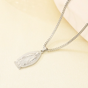 Macro detail of silver Virgin Mary pendant with embossed relief on a stainless box chain