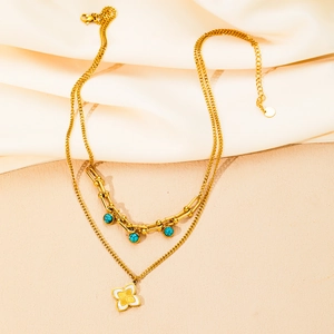 Dettaglio della collana a doppio strato dorata con perle turchesi e ciondolo a fiore