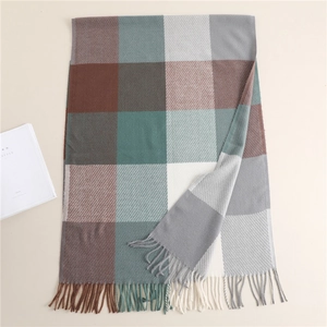 Flat lay of plaid cashmere-like scarf with tassels in brown, green, and grey patterns