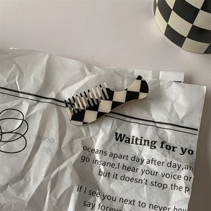 Detail of mini comb hair clip with vintage black and white checkerboard pattern