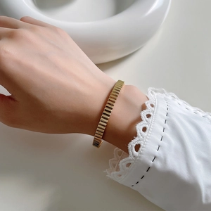 Close-up of a gold-plated irregular wavy texture cuff bracelet worn on a model's wrist