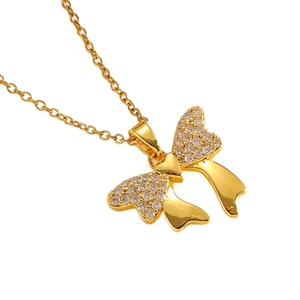 Elegant gold stainless steel bow necklace with crystals and polished finish on white background