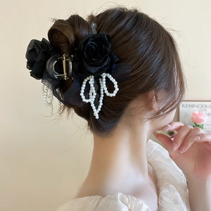 Dettaglio della molletta con rosa di velluto nero, fiocco di perle e nappine eleganti