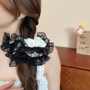 Détail du tissu à pois blancs et de la dentelle noire double couche sur un grand chouchou