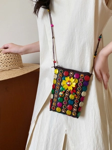Detail of bohemian handmade beaded crossbody bag with a yellow flower on mesh fabric