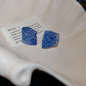 Detailed macro view of irregular blue resin earrings with glitter in a seashell tray