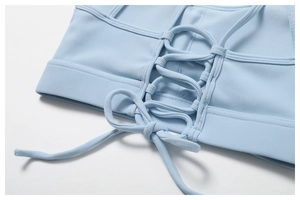 Détail macro d'un haut de yoga côtelé bleu clair avec laçage croisé et nœud papillon au dos