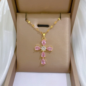 Detailed macro view of a gold cross pendant necklace featuring pink pear-shaped zircons