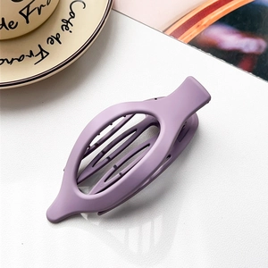 Detail of a large purple matte plastic hair claw clip on a stylish textured surface