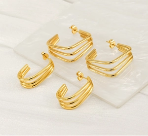 Close-up of geometric hollow gold earrings set on a white marble display plate