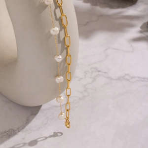 Detail of elegant double-layered gold bracelet with freshwater pearls and paperclip chain