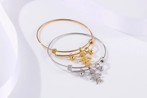 Gros plan de bracelets réglables en or et argent avec breloques garçon sur soie blanche