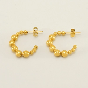 Macro detail of gold beaded hoop earrings featuring polished gradient metallic spheres