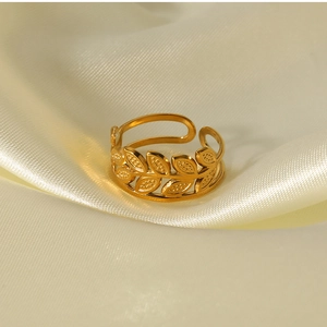 Detailed view of 18k gold plated leaf design open ring on elegant white silk fabric