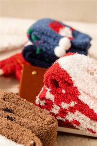 Close-up of stacked colorful coral fleece Christmas socks in red, blue and brown tones