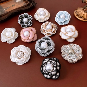 Macro shot of fabric camellia brooches with woven tweed texture and pearl details