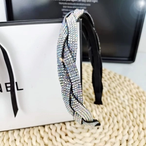 Close-up of a braided headband with iridescent rhinestones on a woven mat surface