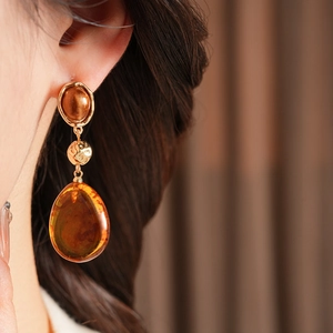 Close-up of amber resin water drop earrings with vintage gold metal on a female model