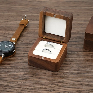 Detail of walnut wood jewelry box with velvet lining holding two wedding rings