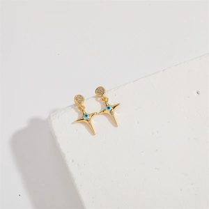 Macro view of gold cross earrings with blue evil eye and crystal accents on stone