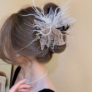 Detail of elegant hair claw clip featuring lace petals, white feathers and pearl tassels