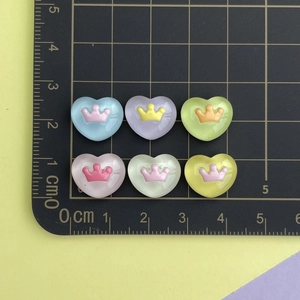 Macro view of 1.5cm resin heart crown charms with a ruler showing the exact product size