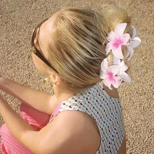 Detail of pink gradient frangipani flower hair clips styled in a neat bun hairstyle