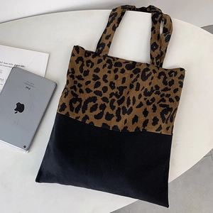 Detail of large leopard print canvas tote bag with a black bottom panel and top handles