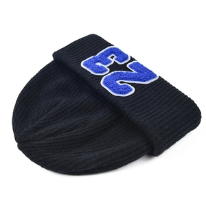 Detalle de gorro de punto acanalado negro con bordado de toalla azul y blanco de letra E2
