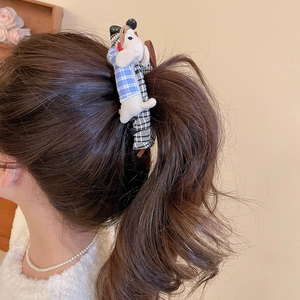 Close-up of a plush dachshund dog hair clip with blue and white gingham patterns on hair