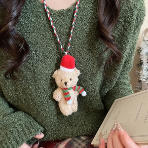 Detail of Christmas plush bear necklace with red hat on dark green sweater