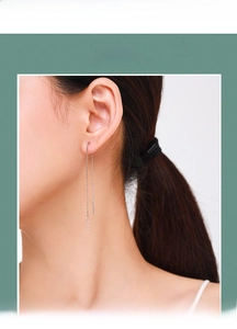 Detail of minimalist S925 sterling silver long chain earrings worn by a model