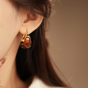 Close-up of model wearing amber resin earrings with gold plating for a refined look