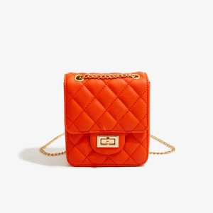 Close-up of orange quilted PU leather crossbody bag with gold chain strap and square lock