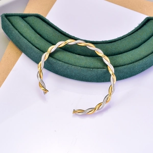 Two-tone twisted cable bangle in gold and silver finish with adjustable open cuff design