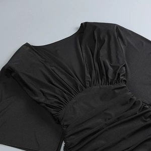 Dettaglio di pieghe e arricciature su un abito aderente nero in tessuto elasticizzato