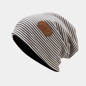 Detail of grey striped knit beanie featuring a leather label and premium fabric texture